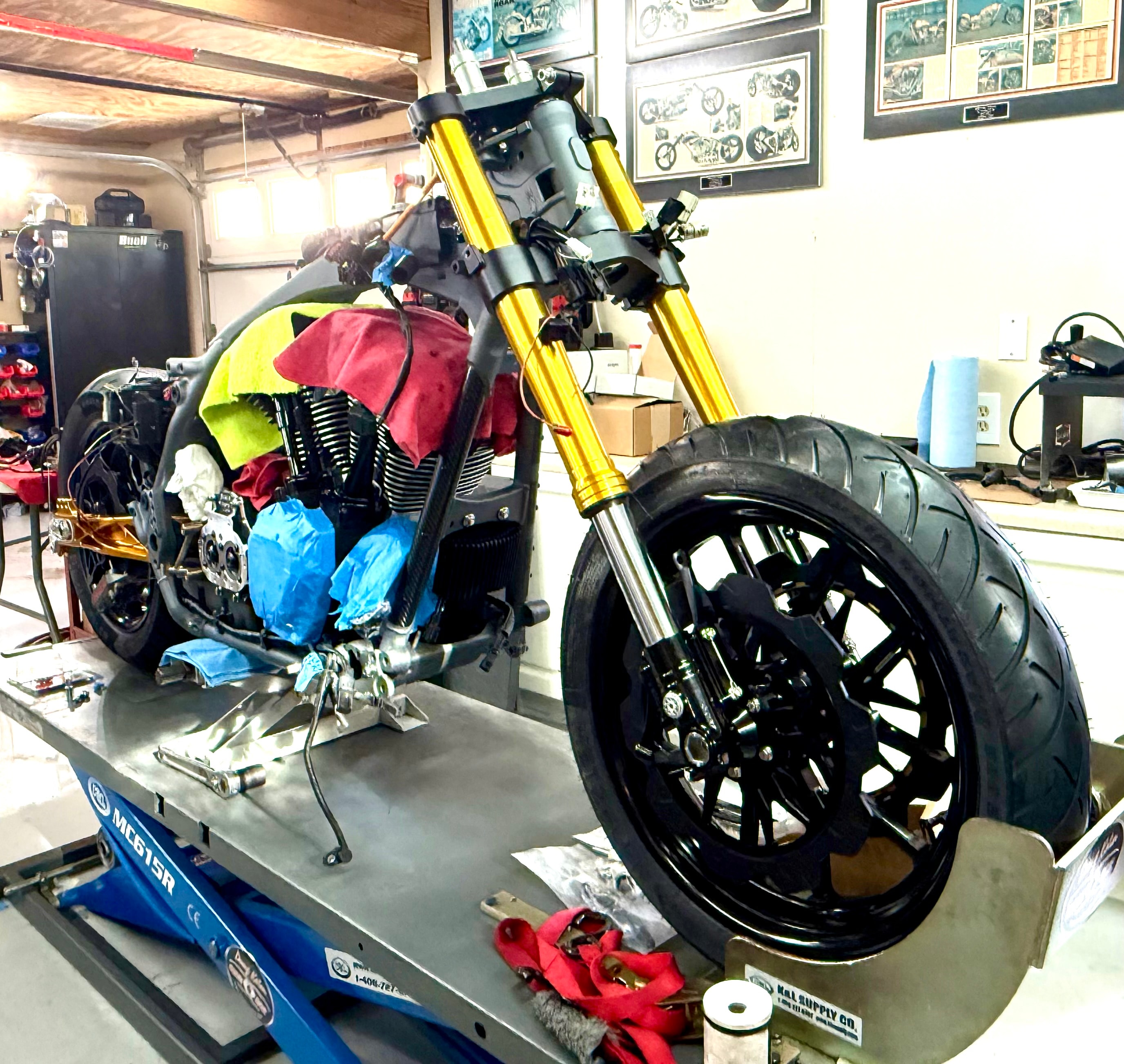 Front end coming together — gold forks, new front wheel, and fresh brakes mounted up.